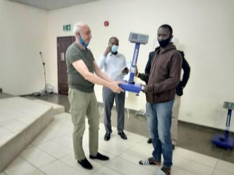 A CTC official presenting the measuring scale to one of the beneficiaries