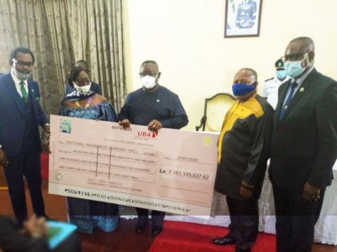 President Bio and NIC officials holding a cheque of the premium