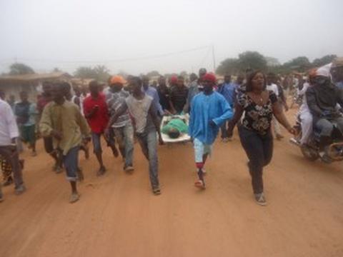 body of one of those killed being taken away by angry relatives and friends