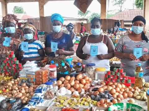 Market Women pose with their vaccination certificates after been jabbed