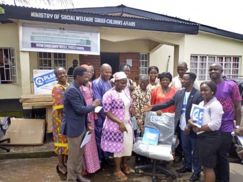 Officials of Plan donating items to officials of Ministry of Social Welfare