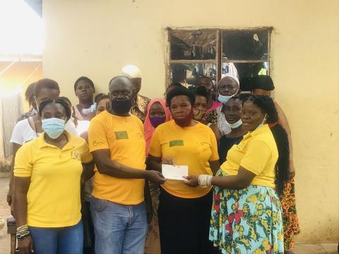 The Project Assistant Coordinator for Rainbow Initiative gives a check of twenty four millions to eight communities in Freetown